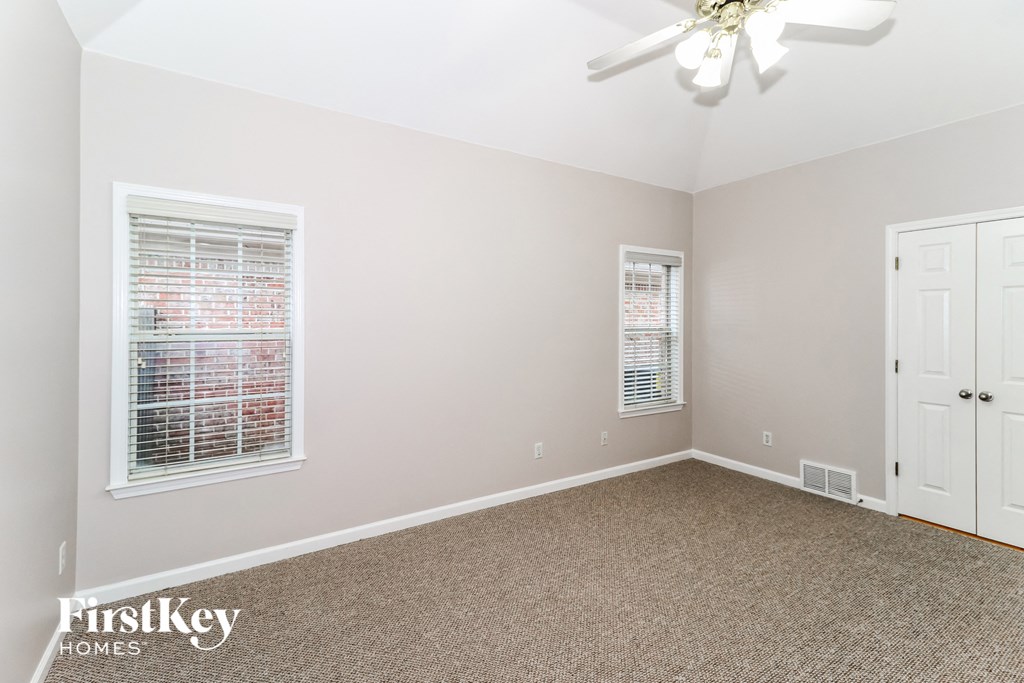 a bedroom with carpet and two windows and a ceiling fan