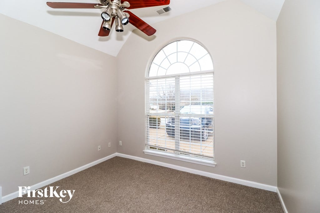 the living room of a home with a large window and a ceiling fan