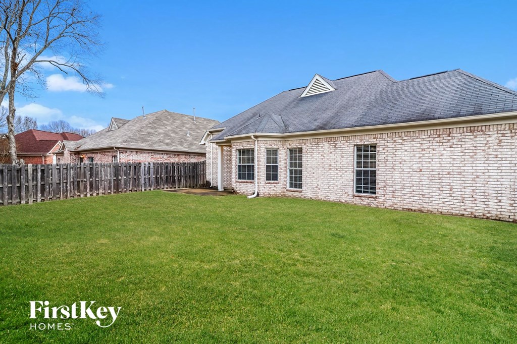 a backyard with a brick house and a wooden fence