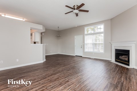 A spacious living room with a fireplace and wood flooring.