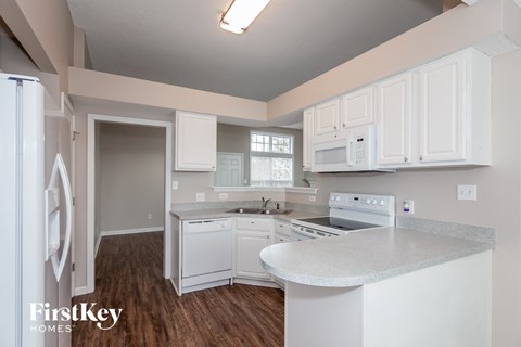 A kitchen with white cabinets and appliances in a house by FirstKey Homes.