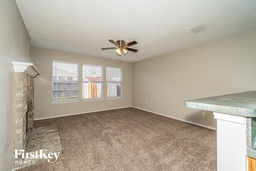 an empty living room with a fireplace and a ceiling fan
