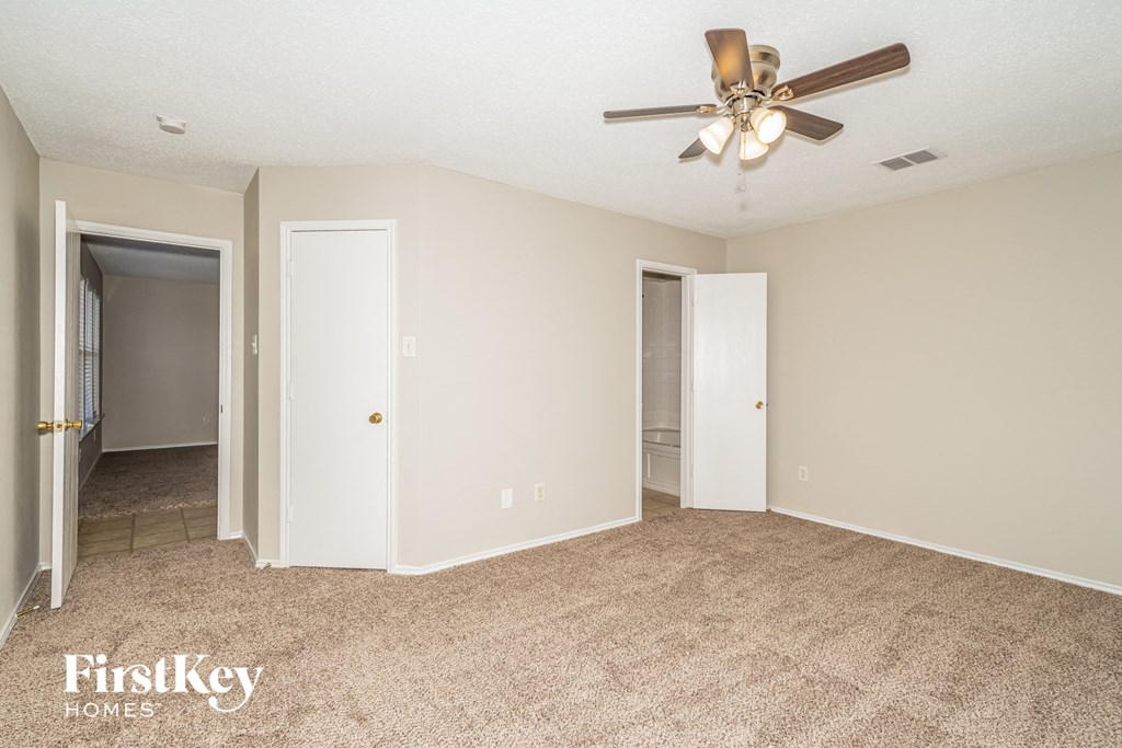 the spacious living room with carpet and a ceiling fan