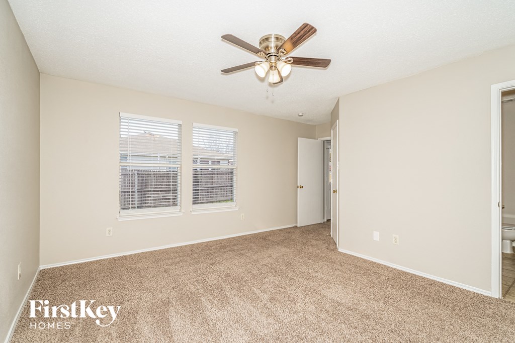 an empty living room with a ceiling fan and two windows