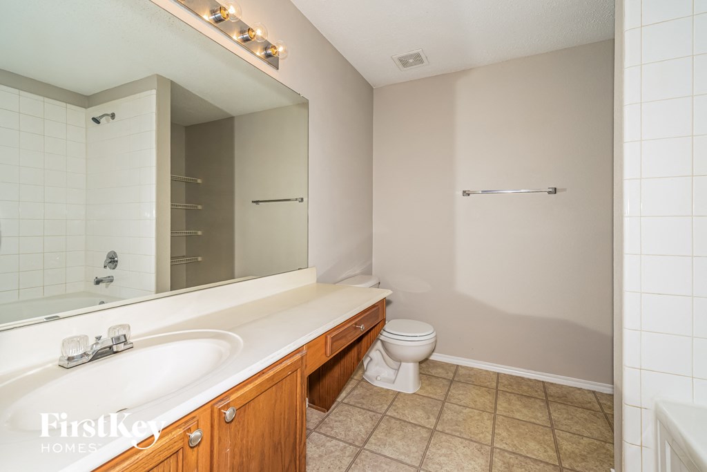 a bathroom with a large mirror and a sink and a toilet