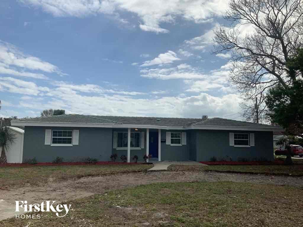 A grey house with a blue door and windows is for sale.