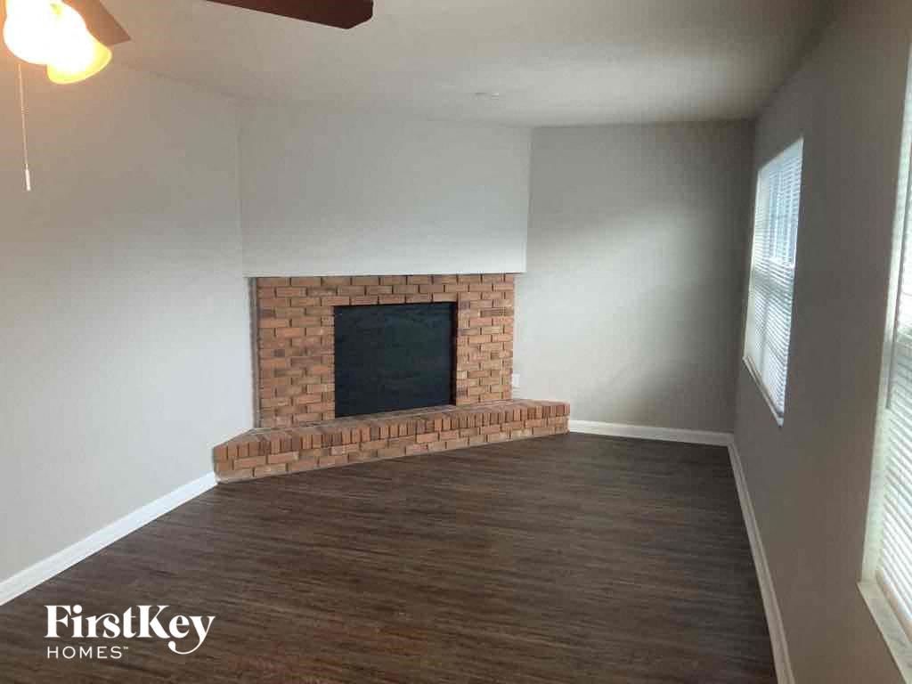 A living room with a brick fireplace and wooden flooring.