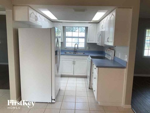 A kitchen with white cabinets and a white refrigerator.