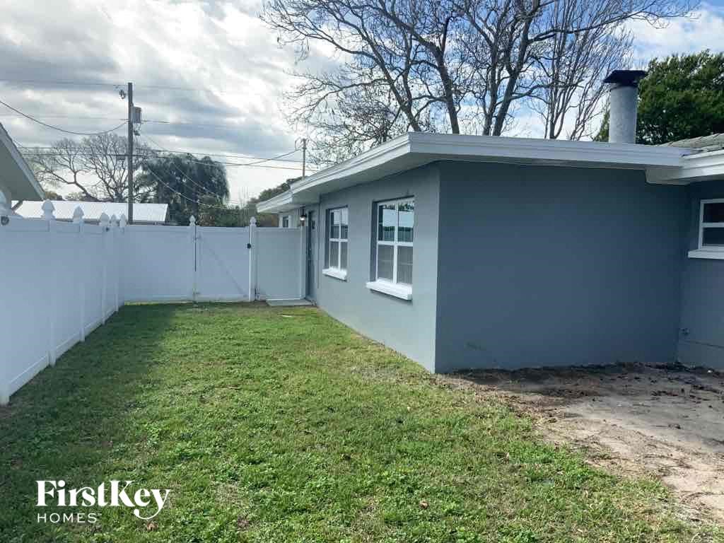 A small house with a fence and a grassy yard.