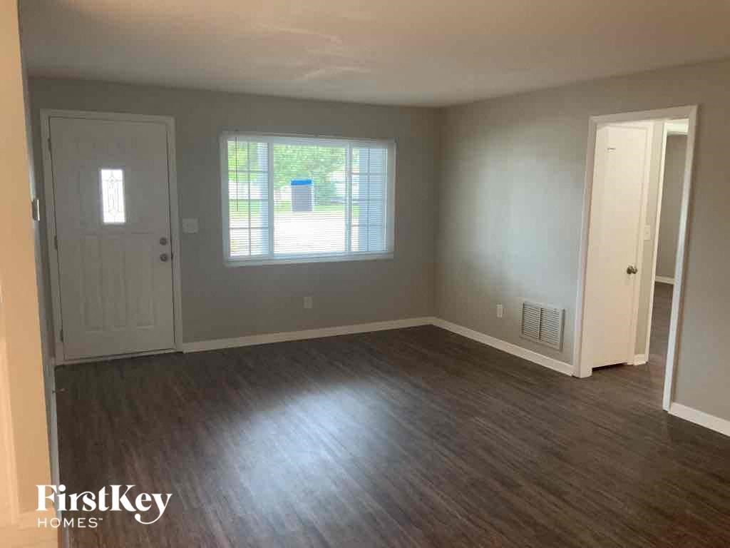 A room with wooden flooring and a window with a view of a street.