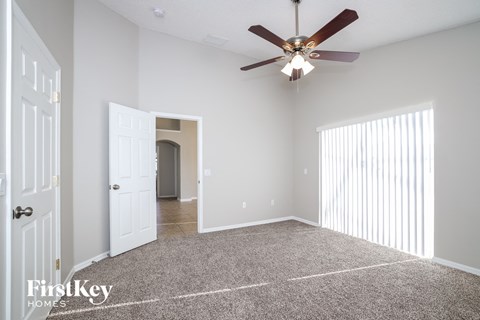 a living room with a ceiling fan and a carpet
