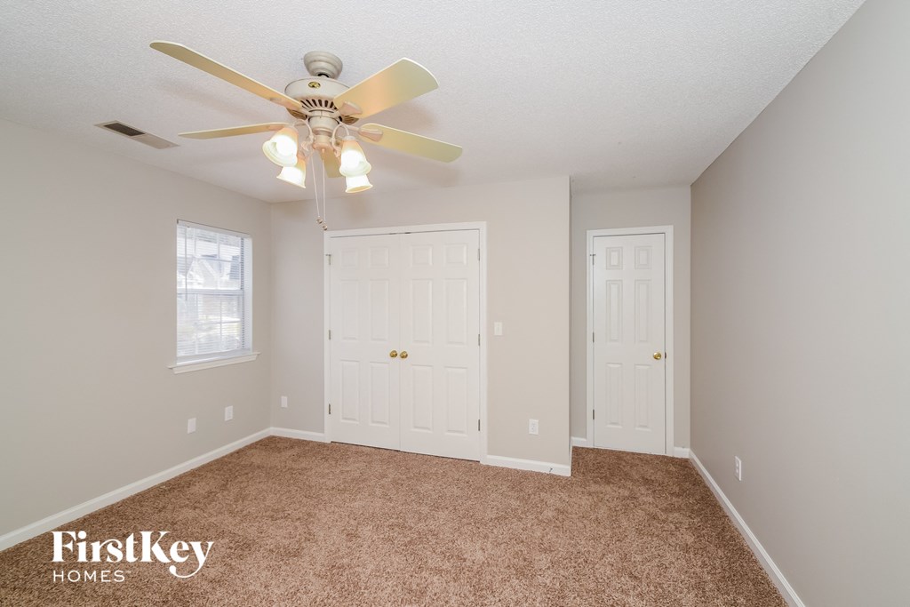 the master bedroom has carpet and a ceiling fan