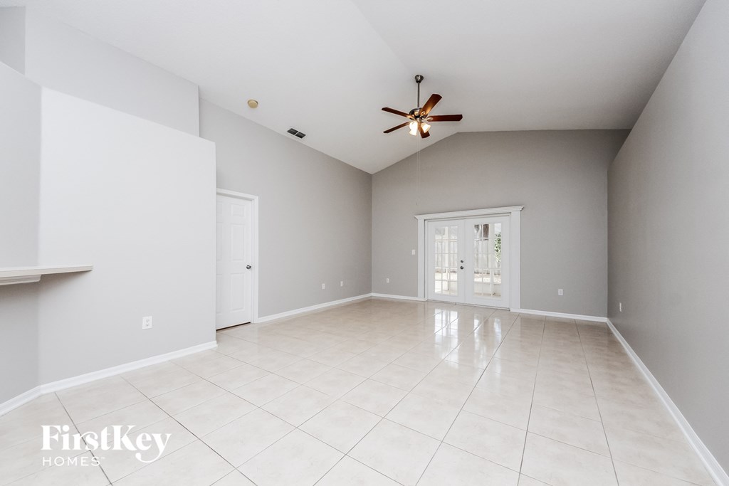 A spacious room with a ceiling fan and tiled flooring.
