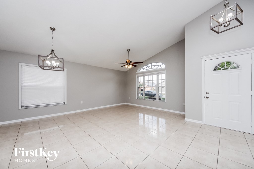 A spacious room with a ceiling fan and a window with a view of a living room.