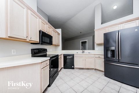A kitchen with a black fridge and white cabinets.