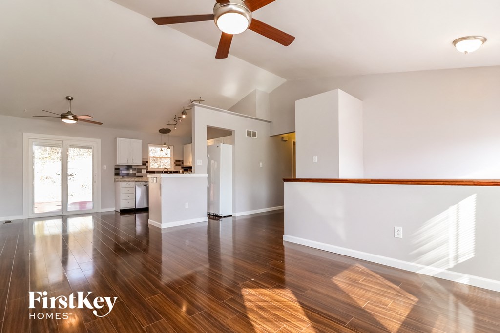 A spacious room with wooden floors and a ceiling fan.