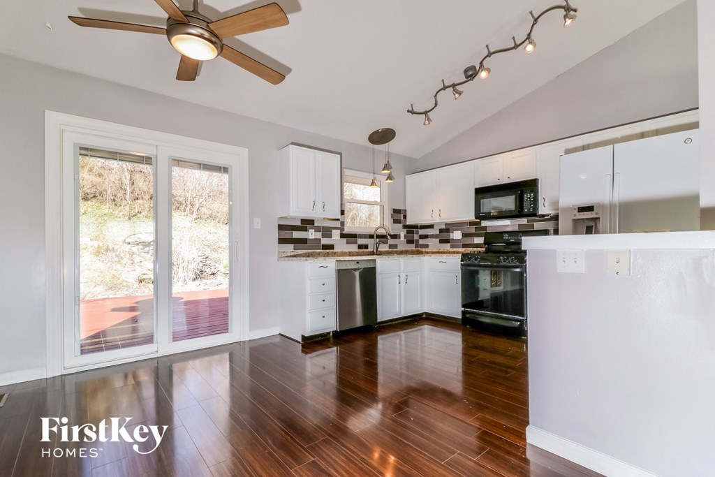A modern kitchen with a wood floor and white walls.