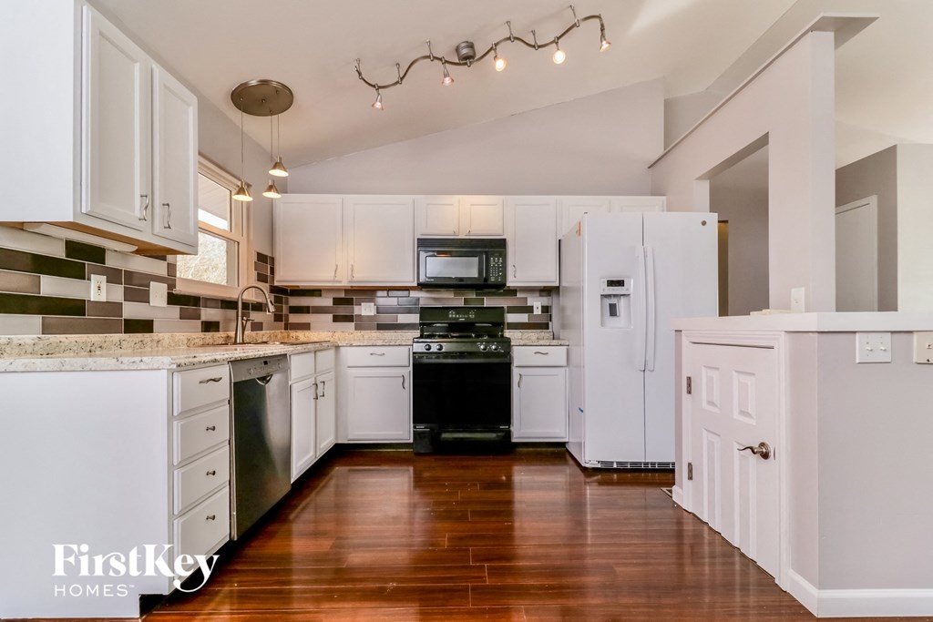 A kitchen with white cabinets and a wooden floor.