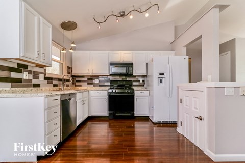 A kitchen with white cabinets and a wooden floor.