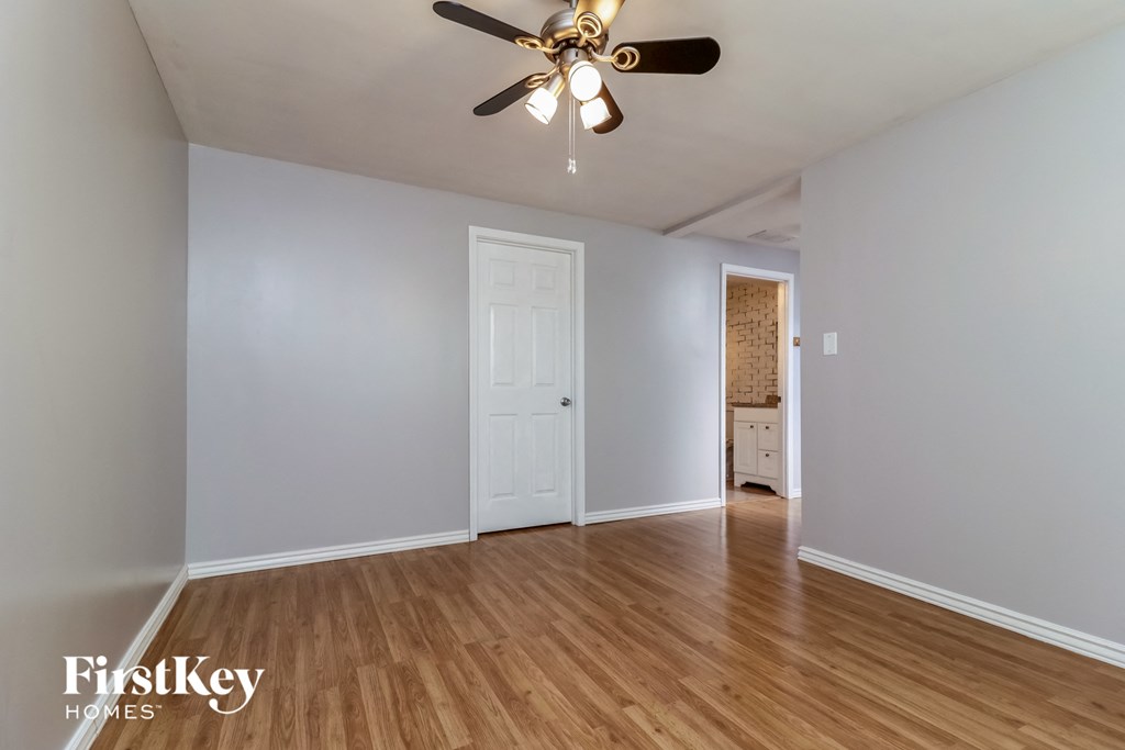 A room with a ceiling fan and wooden floors.