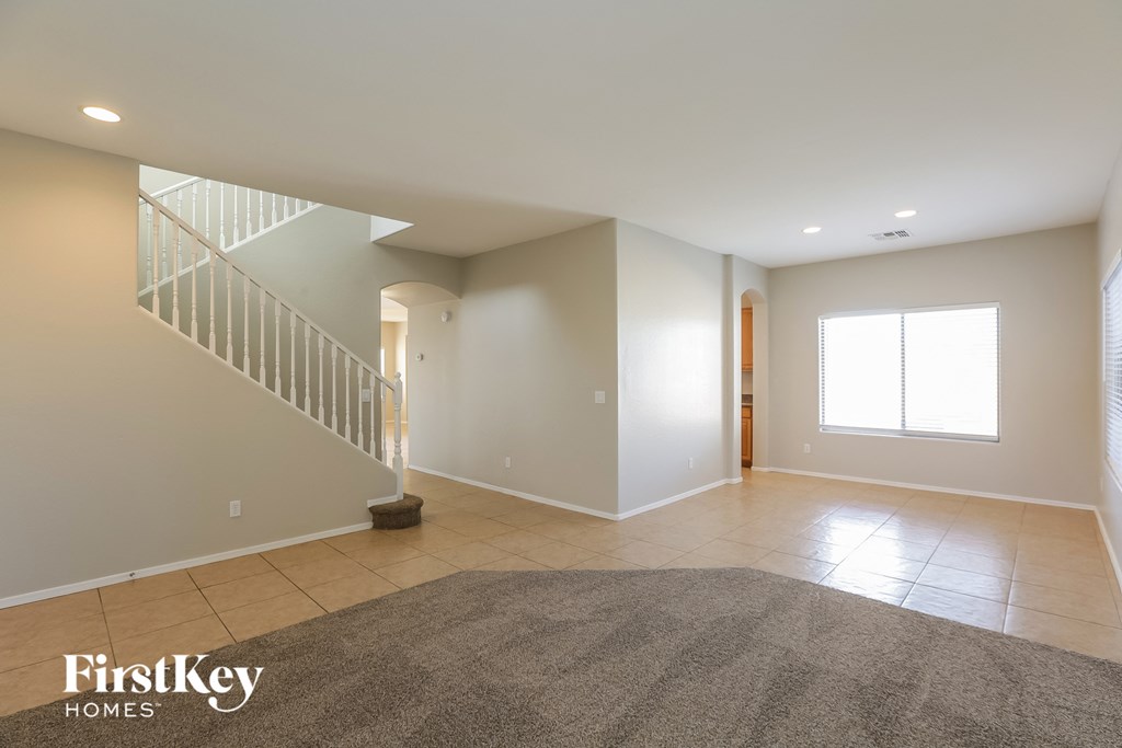 an empty living room with a staircase and a tile floor