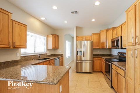 a kitchen with wooden cabinets and granite counter tops and a stainless steel refrigerator