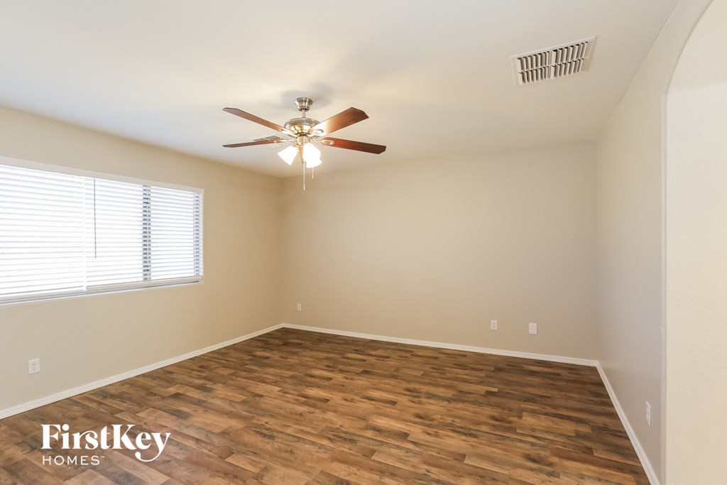the spacious living room with hardwood flooring and a ceiling fan