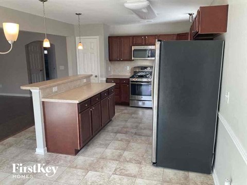 A kitchen with a black refrigerator and brown cabinets.