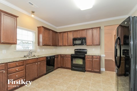 A kitchen with brown cabinets and a black refrigerator.