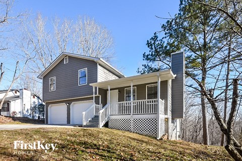 a gray house with a porch on a hill