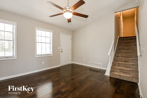 an empty living room with a ceiling fan and a staircase