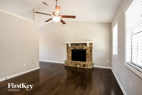 a living room with a stone fireplace and a ceiling fan