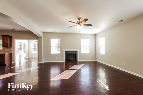 A spacious living room with a fireplace and a ceiling fan.