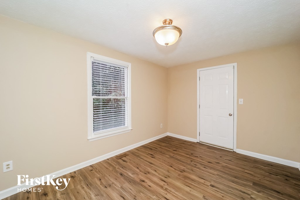 an empty living room with a white door and a window