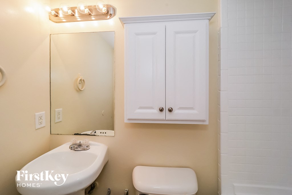 a bathroom with a sink toilet and a mirror and a cabinet