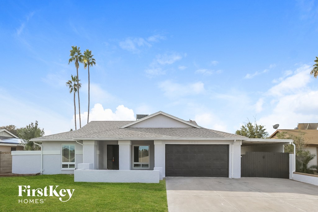 A house with a garage and a palm tree in front.