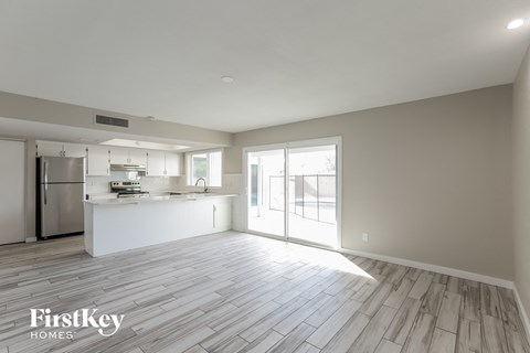 A spacious kitchen and living room with wooden flooring and a refrigerator.