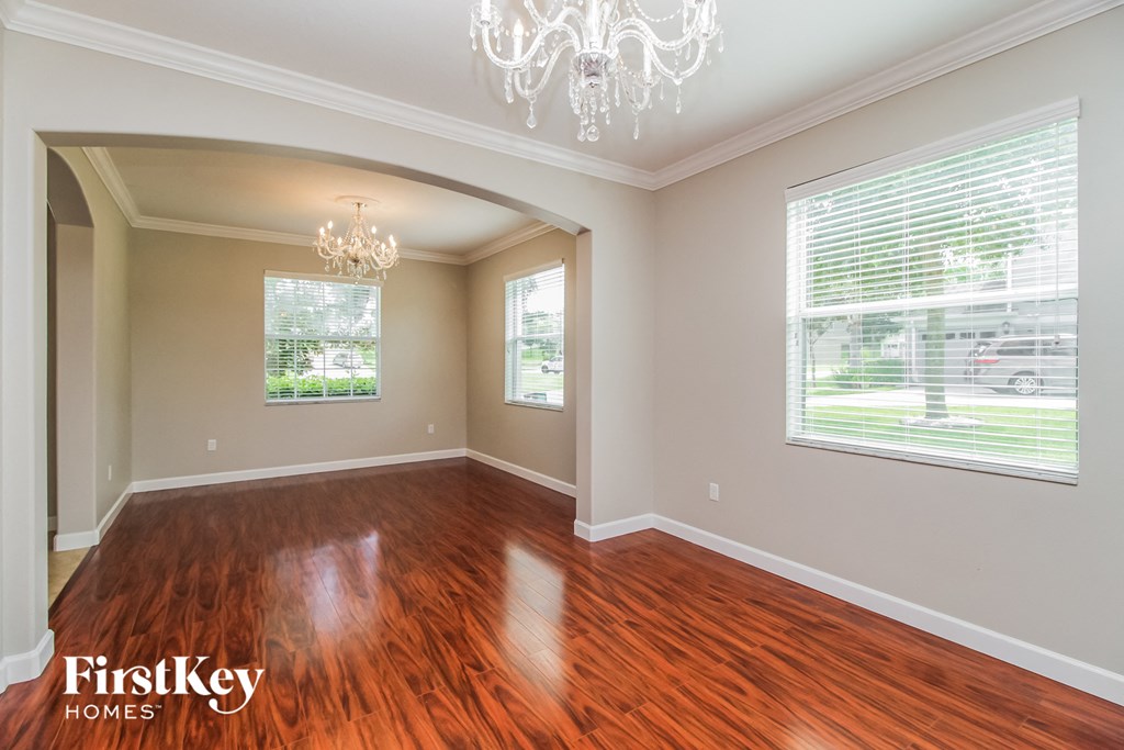 an empty living room with wood floors and a chandelier