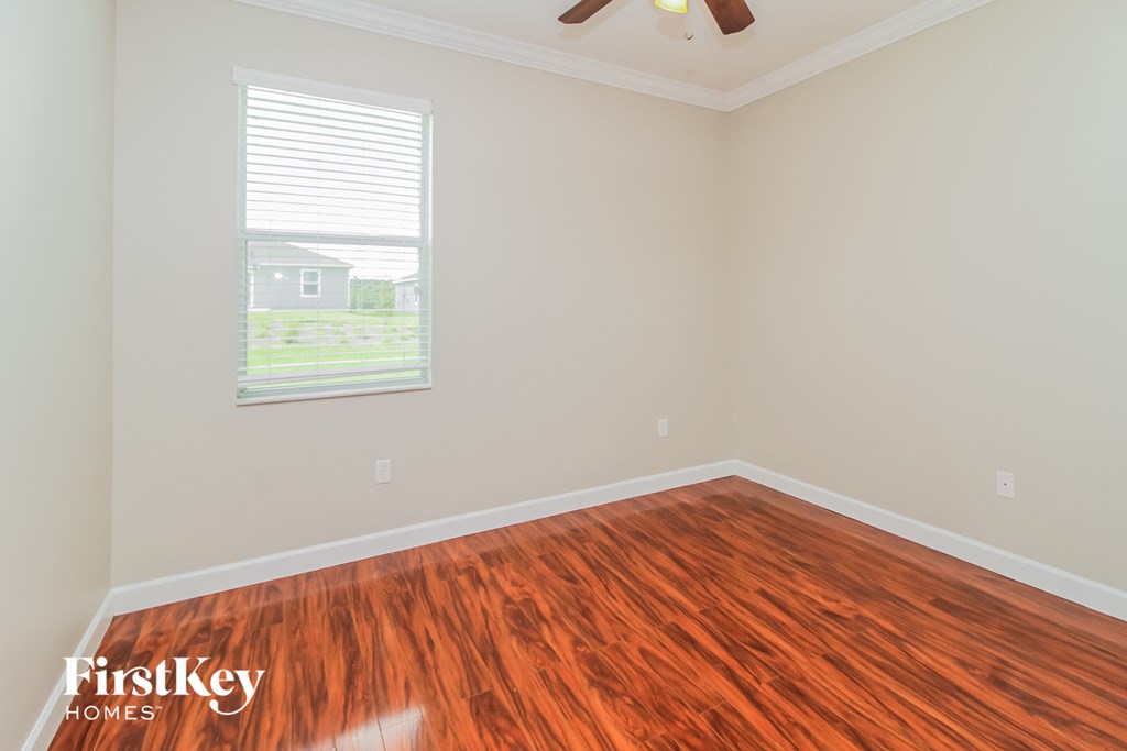 a bedroom with wood flooring and a window