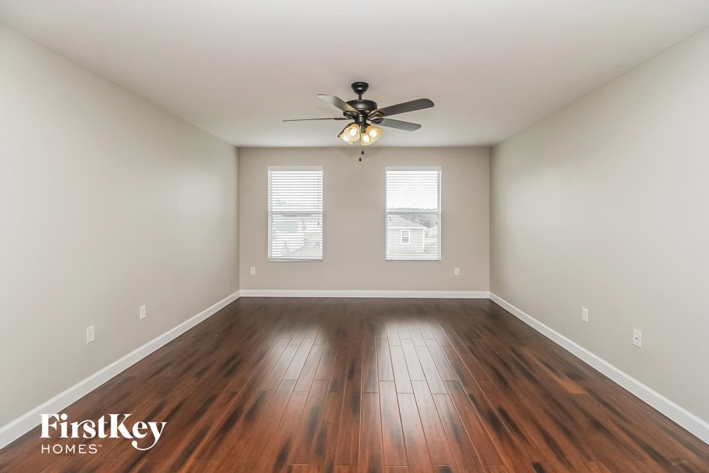 an empty living room with wood floors and a ceiling fan