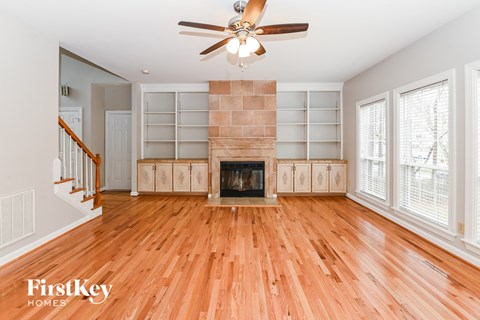 A spacious living room with a fireplace and wood flooring.