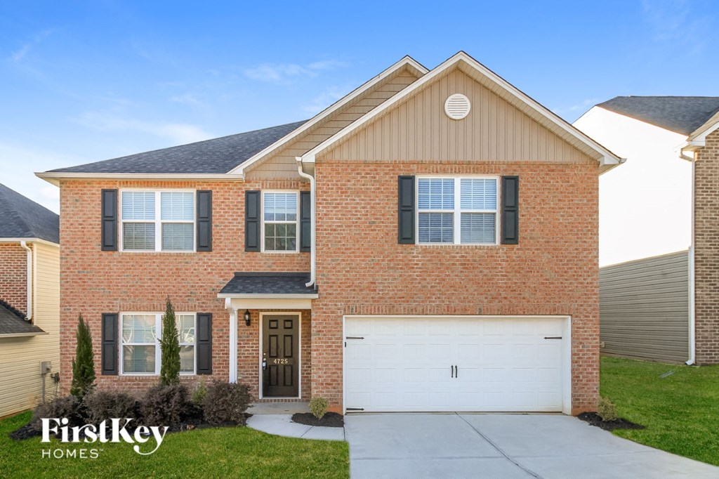 A brick house with a black garage door and a white garage door.