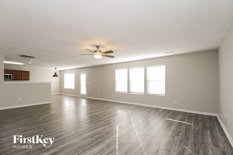 A spacious room with wooden flooring and a ceiling fan.