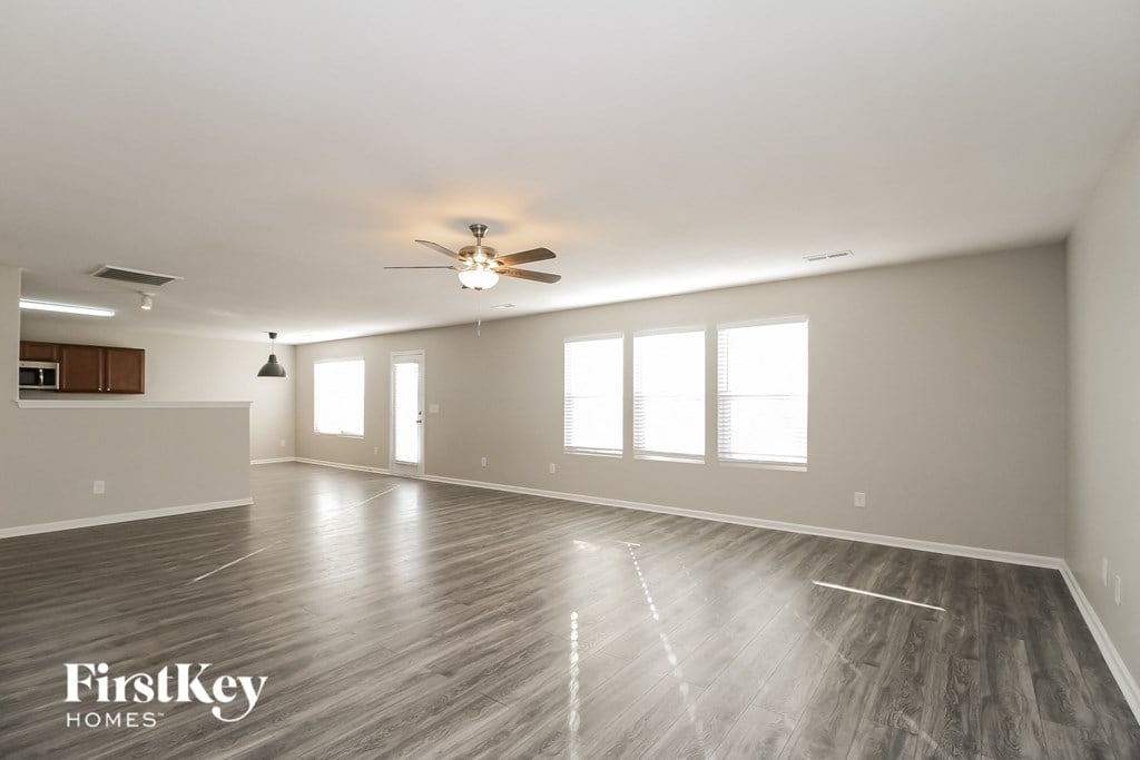 A spacious room with wooden flooring and a ceiling fan.