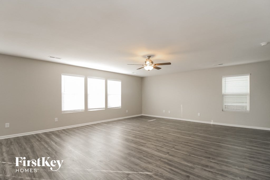 A spacious room with a ceiling fan and wooden flooring.