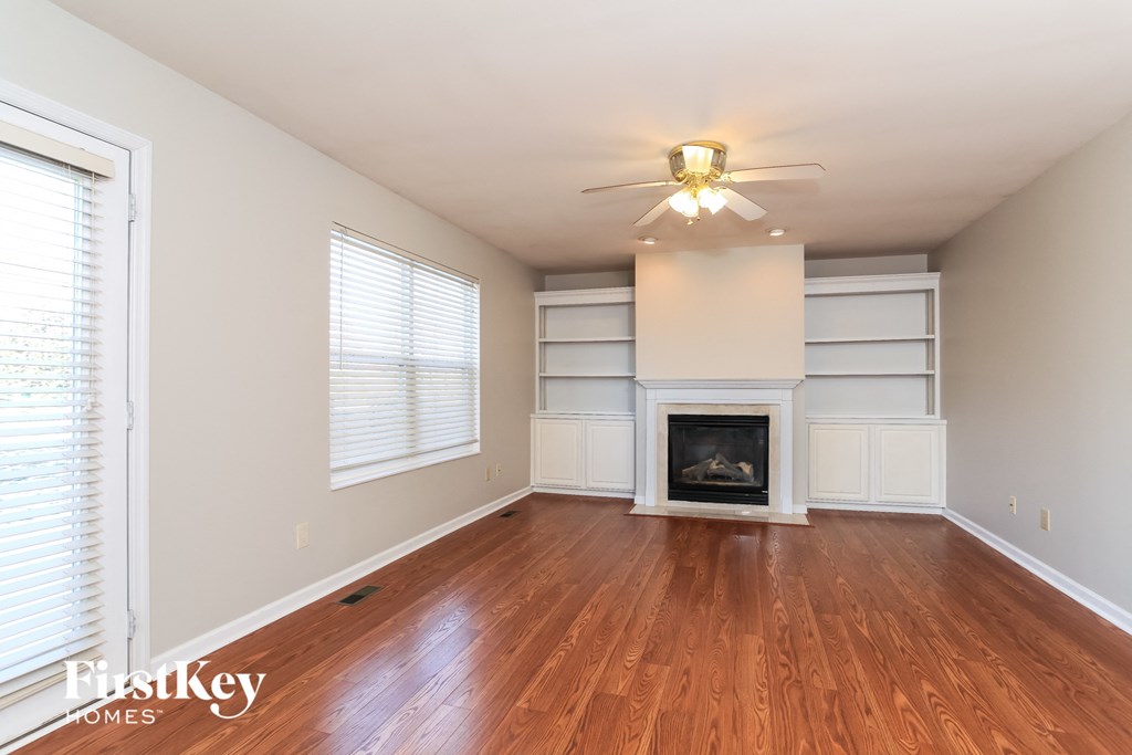 A well-lit, empty room with a fireplace and wooden floors.