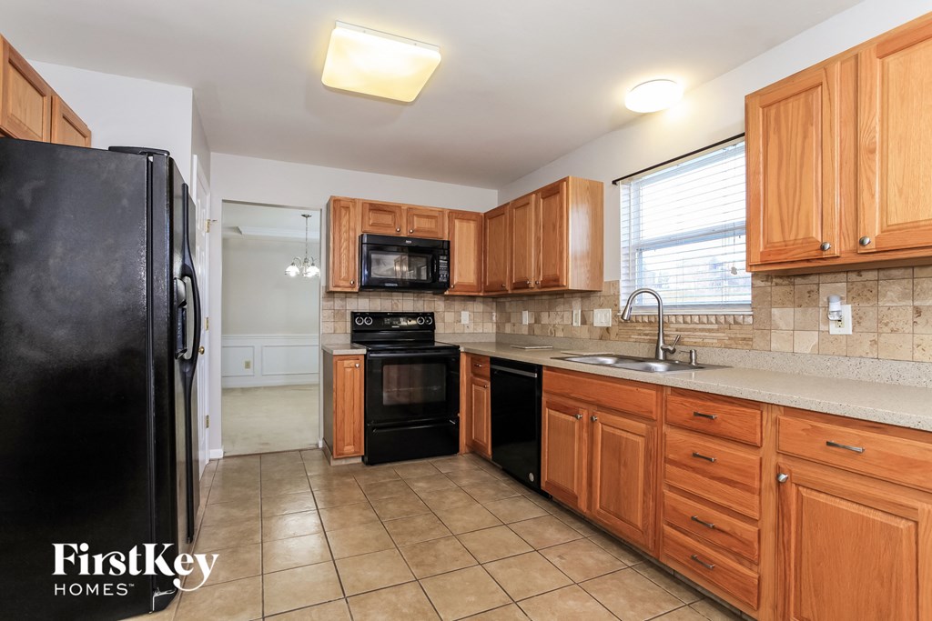 A kitchen with wooden cabinets and a black fridge.