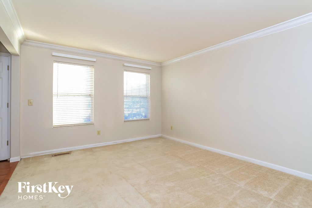 A room with a carpeted floor and two windows.