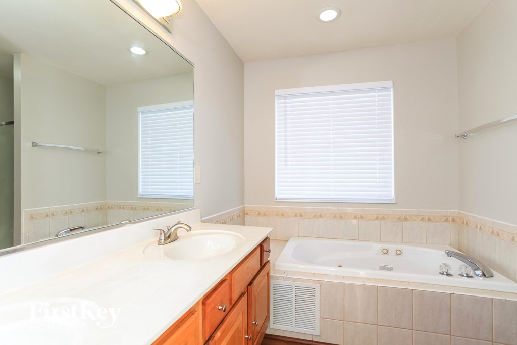 A white bathroom with a sink, mirror, and bathtub.