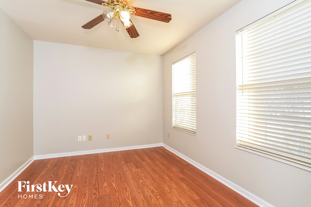 A room with a ceiling fan and wooden floors.